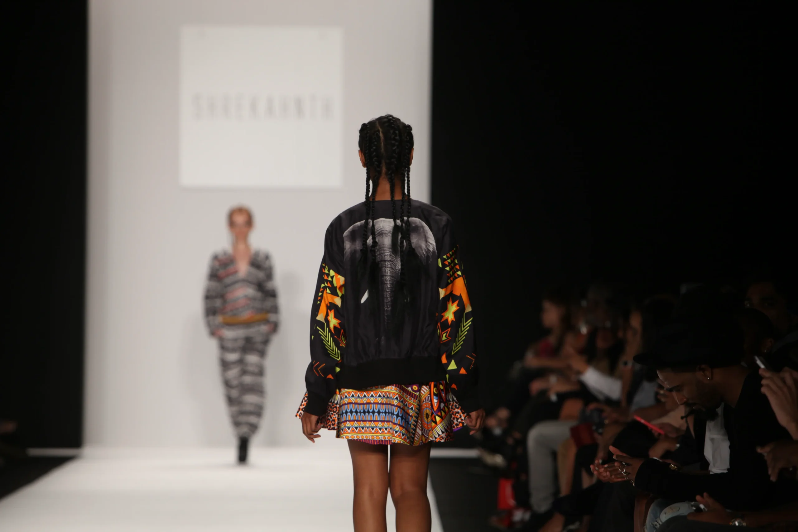طبعات حيوانات وتصاميم قبلية حصرية: إبداع في أسبوع الموضة بنيويورك – ربيع/صيف 2015 36 Runway moment with a seated audience, featuring a model showcasing the back of an animal print bomber jacket.